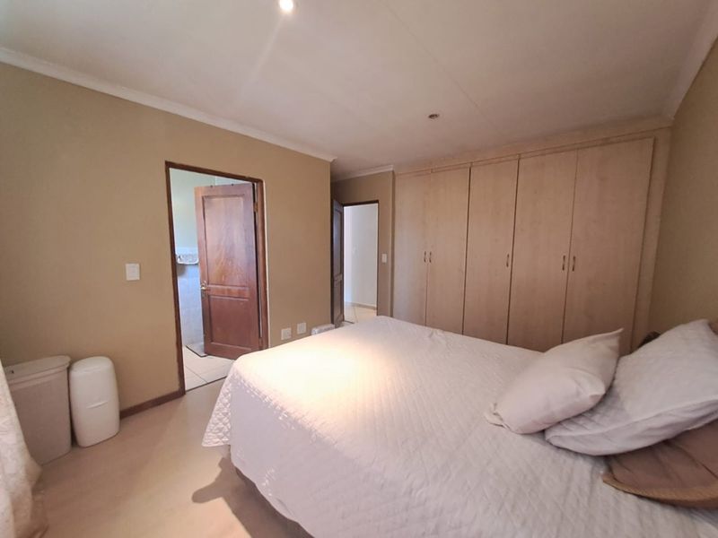 A bedroom featuring built-in wooden cupboards, neutral wall tones, and direct access to an adjoining bathroom.
