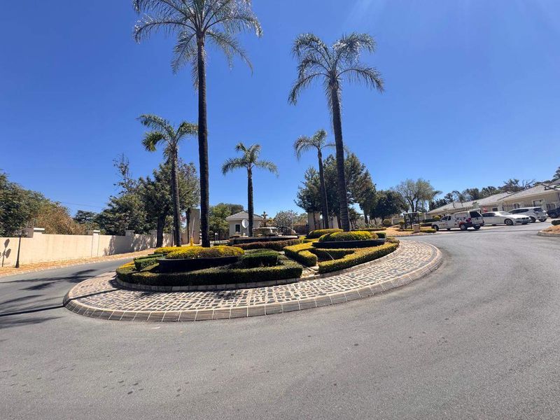 A well-maintained entrance roundabout featuring mature palm trees and manicured landscaping within the apartment complex grounds.