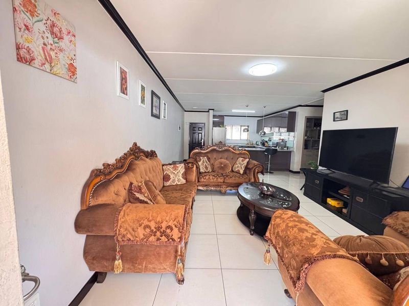 Open-plan living area featuring tiled flooring and a seamless transition into a functional kitchen space with a breakfast bar.