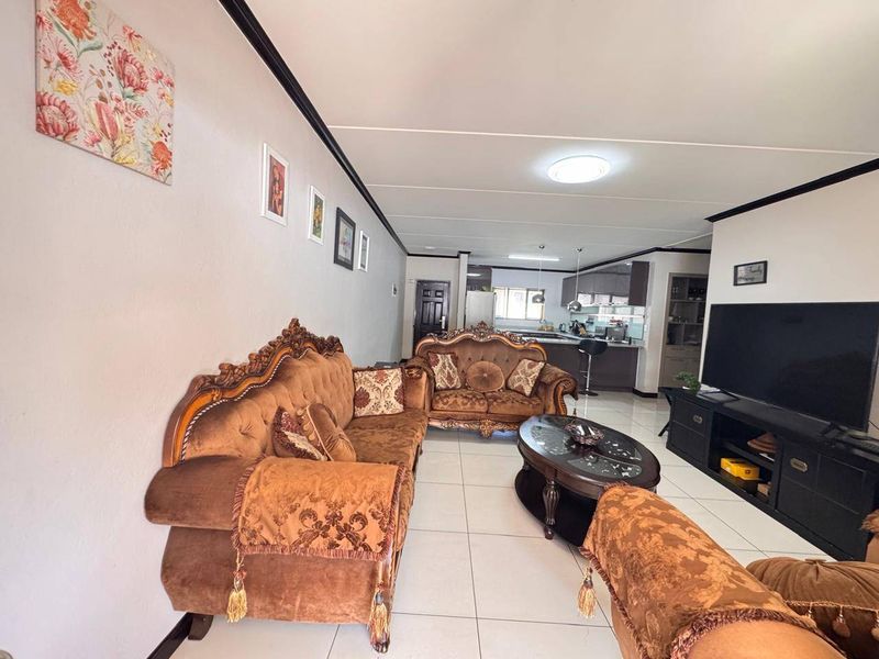 Spacious open-plan living area featuring tiled flooring and a modern kitchen with island, creating a seamless flow between cooking and relaxation spaces.
