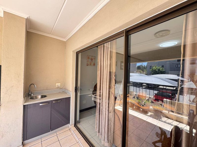 Covered balcony featuring a convenient built-in kitchenette with sink and cabinetry, accessible via large sliding glass doors.