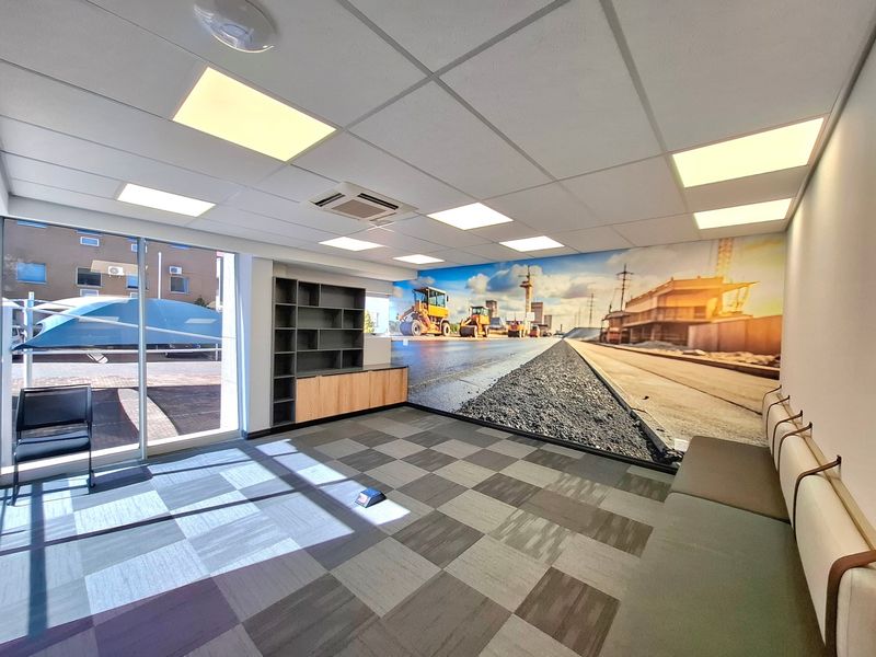 Modern commercial office space featuring a suspended ceiling with recessed lighting, ducted air conditioning, built-in shelving, and large sliding glass doors.