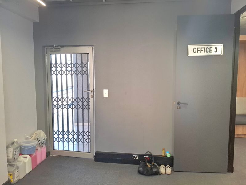 A commercial hallway featuring a secure metal gate entrance and a designated office door with signage.