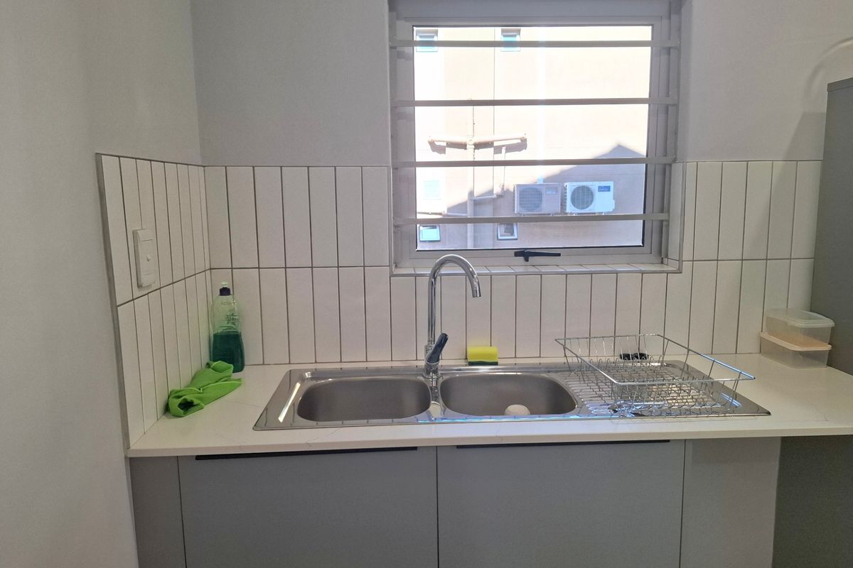 A clean and functional scullery area featuring a double bowl stainless steel sink, modern chrome tap, and contemporary vertical subway tile backsplash.