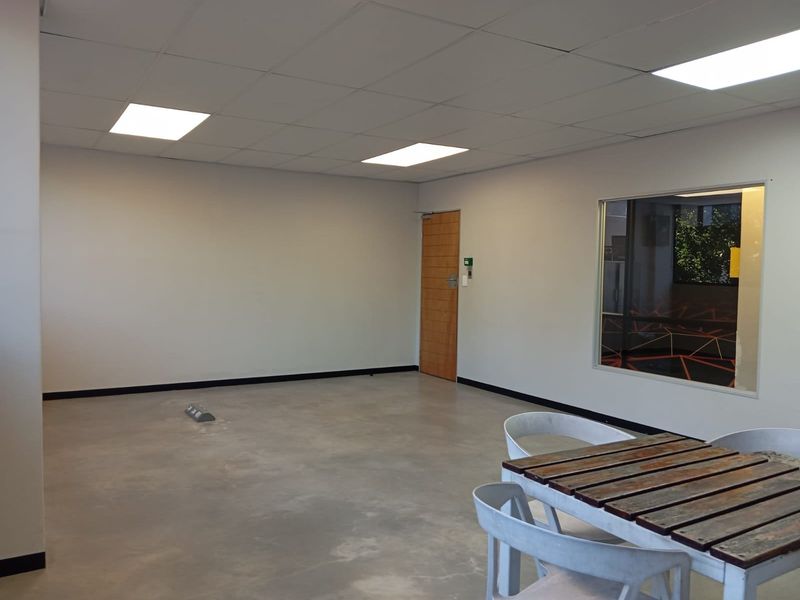 A spacious, open-plan commercial office area featuring polished concrete flooring, recessed ceiling lighting, and a large interior glass partition.