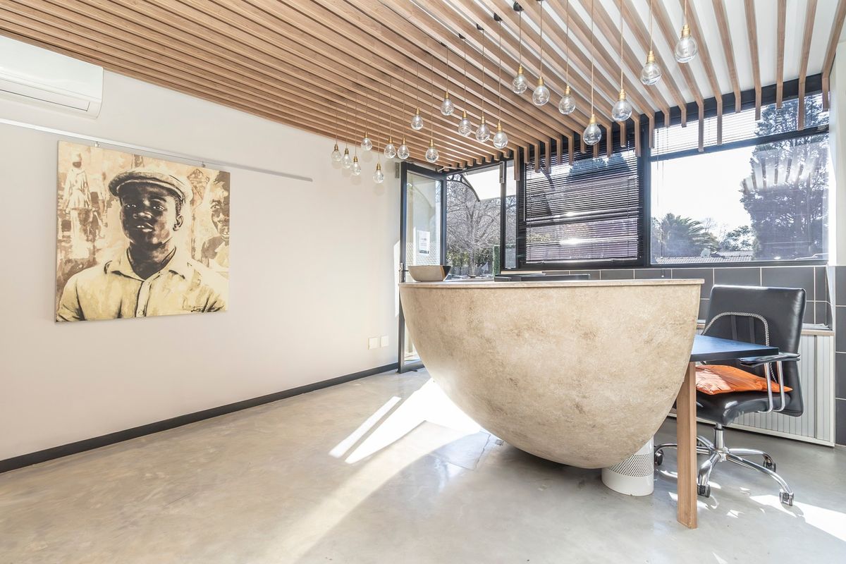 Modern commercial office space featuring a unique curved reception desk, polished concrete floors, and a stylish slatted timber ceiling with pendant lighting.