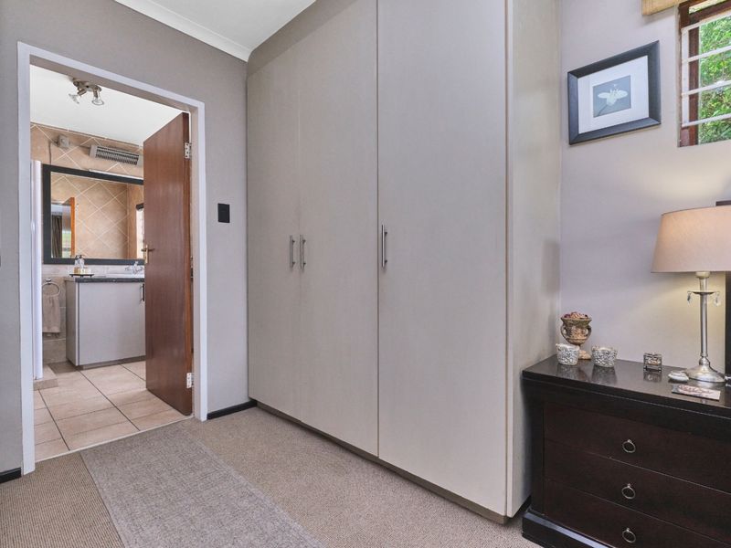 A well-maintained bedroom featuring neutral walls, fitted built-in cupboards, and direct access to an en-suite bathroom.