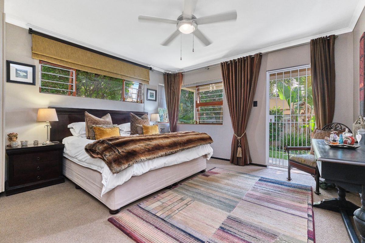 Spacious bedroom featuring carpeted flooring, a ceiling fan, and direct access to the garden through a secure gate.