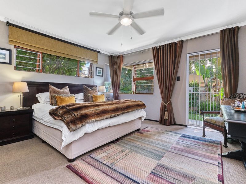 Spacious bedroom featuring carpeted flooring, a ceiling fan, and direct access to the garden through a secure gate.