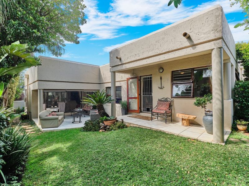 Rear view of the cluster property featuring a covered patio area, tiled flooring, concrete structural columns, and a well-maintained private garden.