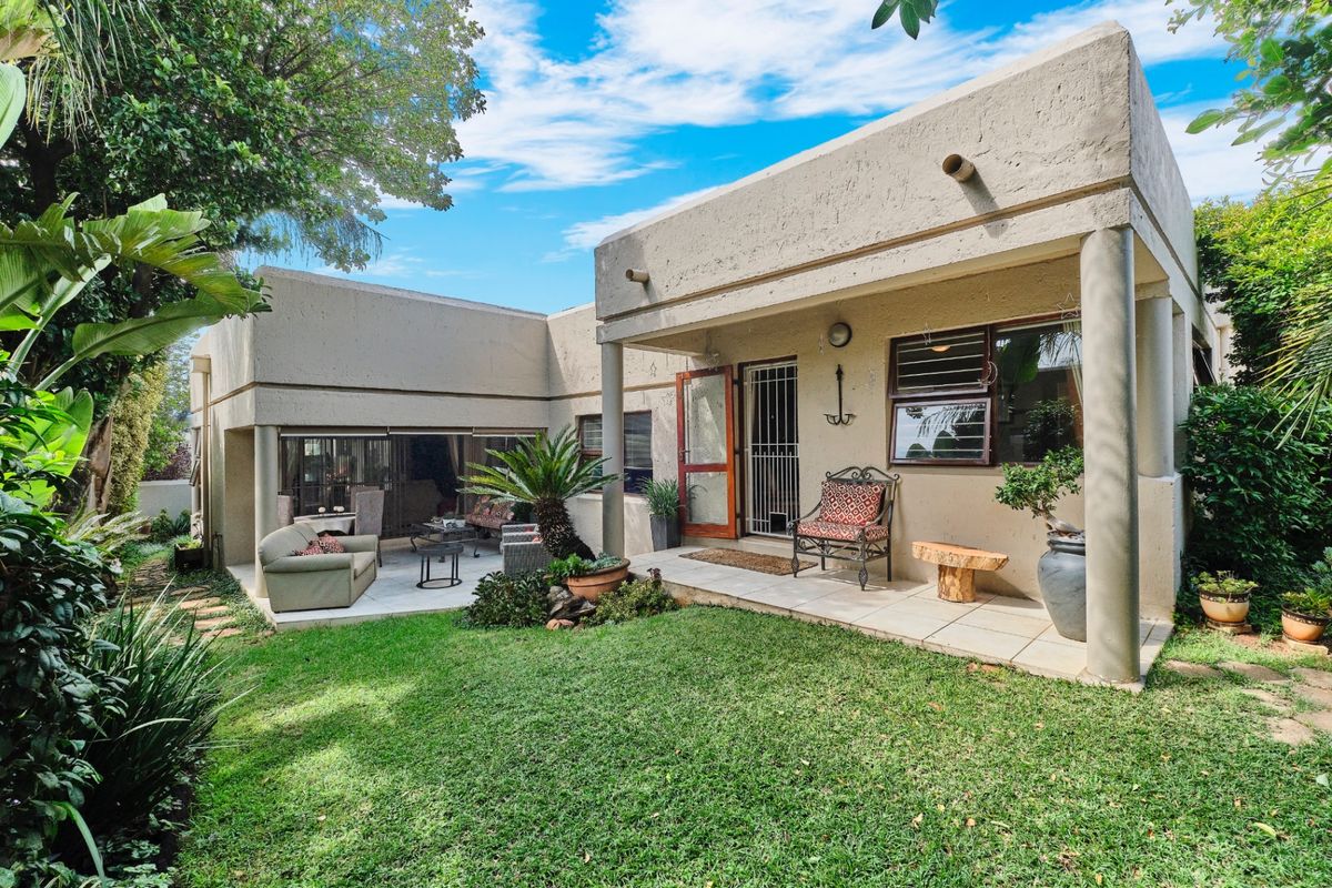 Rear view of the cluster property featuring a covered patio area, tiled flooring, concrete structural columns, and a well-maintained private garden.