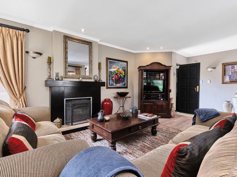 A comfortable living room featuring a prominent fireplace, laminate flooring, and recessed lighting, creating a warm and inviting atmosphere.