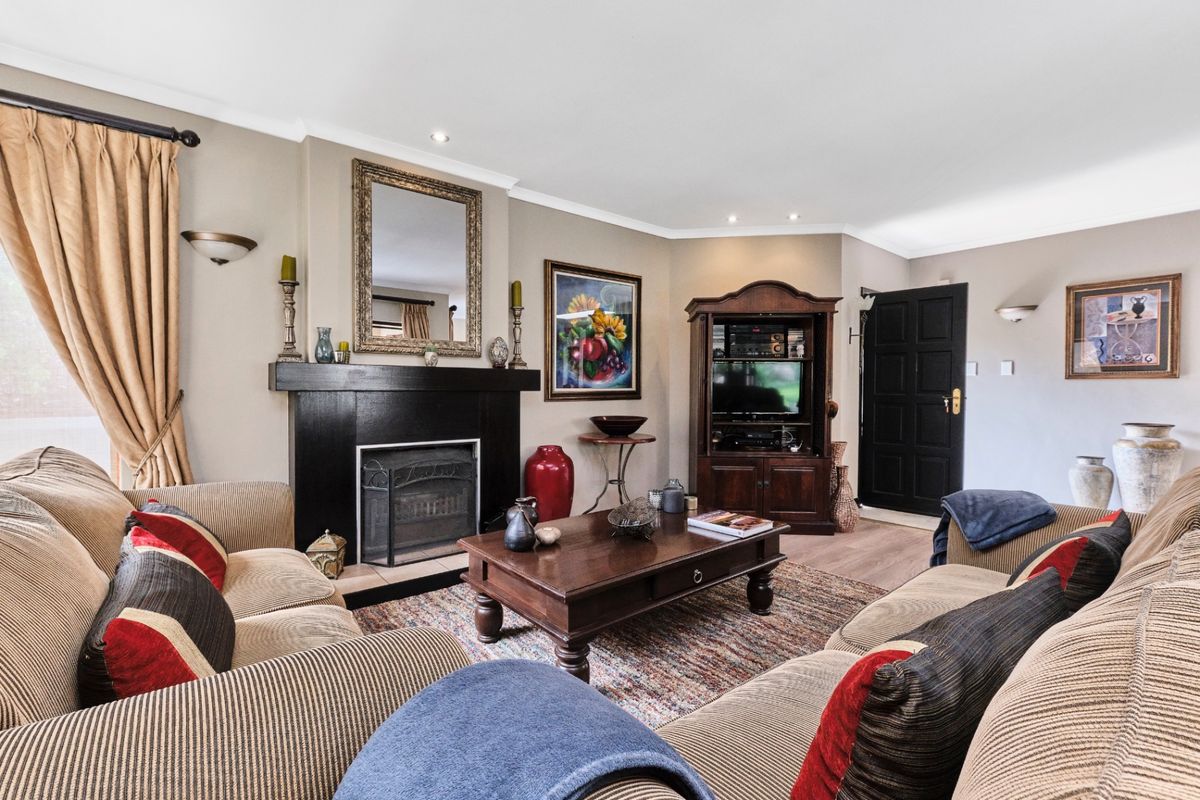 A comfortable living room featuring a prominent fireplace, laminate flooring, and recessed lighting, creating a warm and inviting atmosphere.