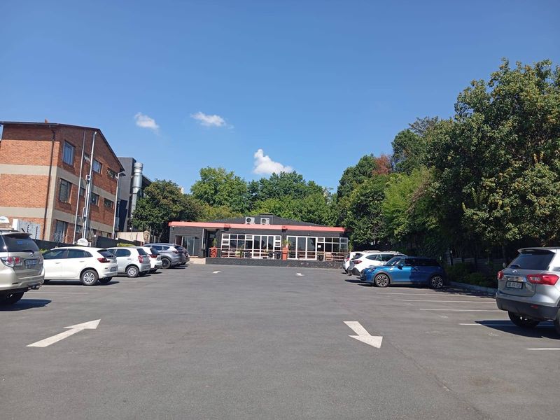 Commercial property exterior featuring a paved parking area and a modern storefront with large glass windows and brick facade.
