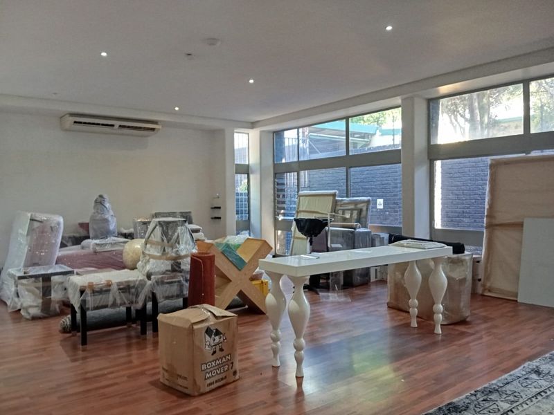 Spacious open-plan commercial area featuring laminate timber flooring, recessed downlighting, wall-mounted air conditioning, and large windows providing ample natural light.