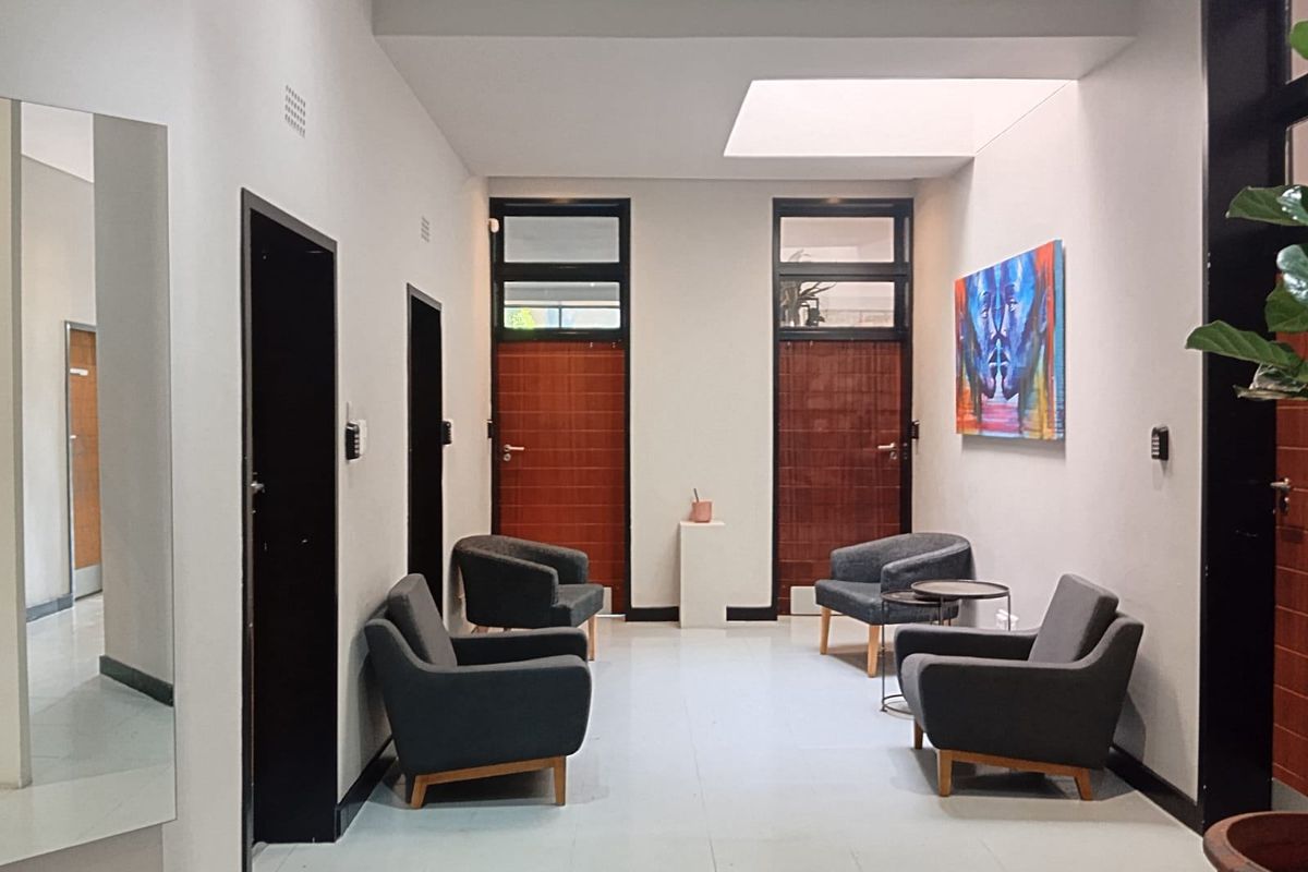 A bright and modern commercial hallway featuring tiled flooring, a large skylight, and multiple access doors, providing a clean and professional reception or waiting area.