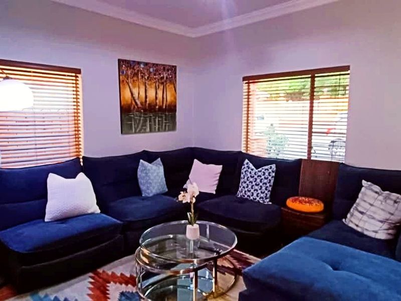 A comfortable living room featuring wooden blinds, a solid timber door, and decorative cove cornicing, providing a functional and inviting space.