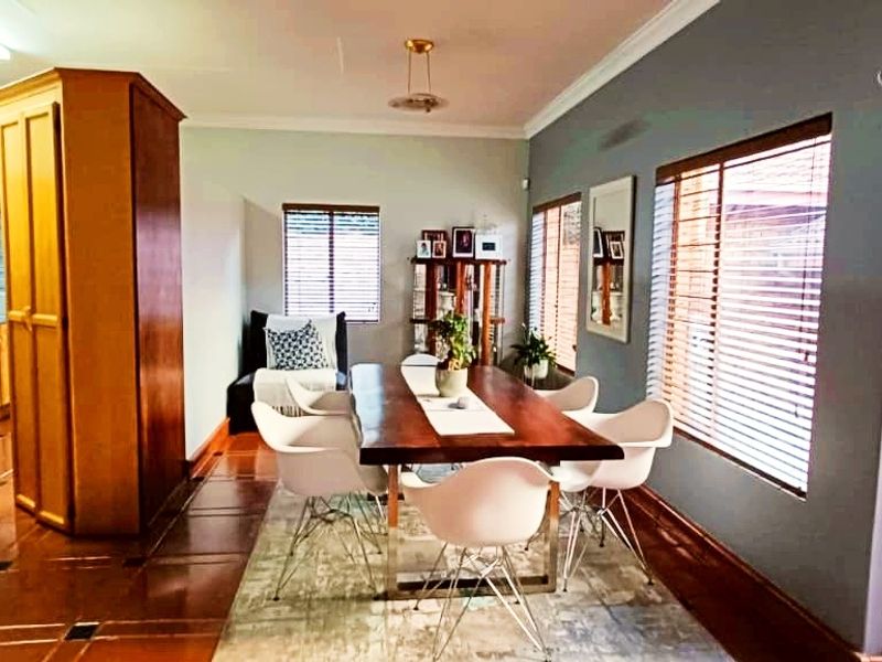 Open-plan dining area featuring tiled flooring, large windows with venetian blinds, and direct access to an outdoor patio space.