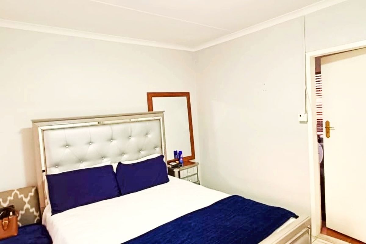 A standard bedroom featuring neutral walls, cove cornicing, and a doorway leading to an adjacent space.