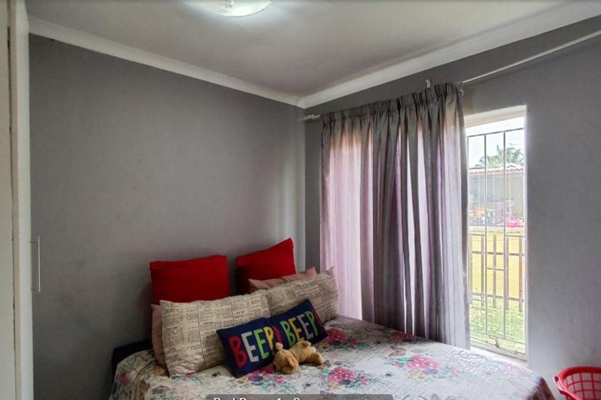 A bedroom featuring grey walls, a built-in wardrobe, and a window fitted with security bars, providing natural light and functional storage space.