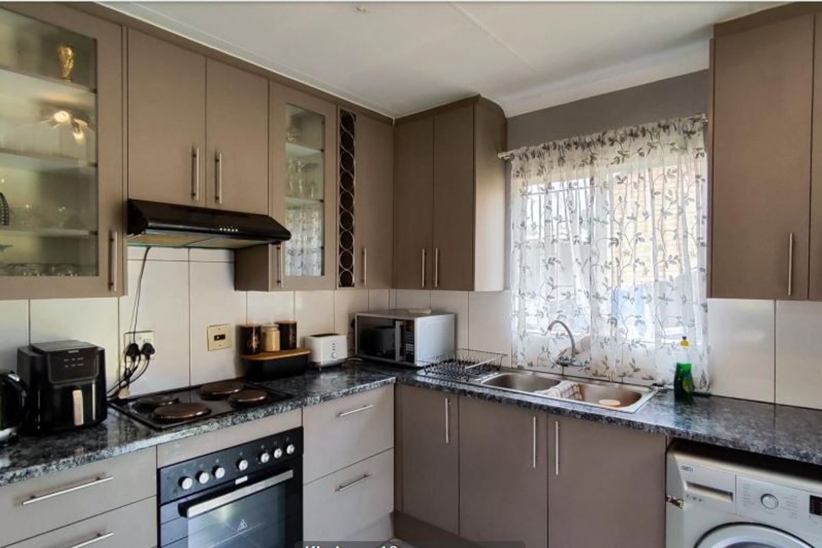 A functional kitchen featuring modern taupe cabinetry, granite-look laminate countertops, a built-in oven with electric hob, and a double bowl sink.
