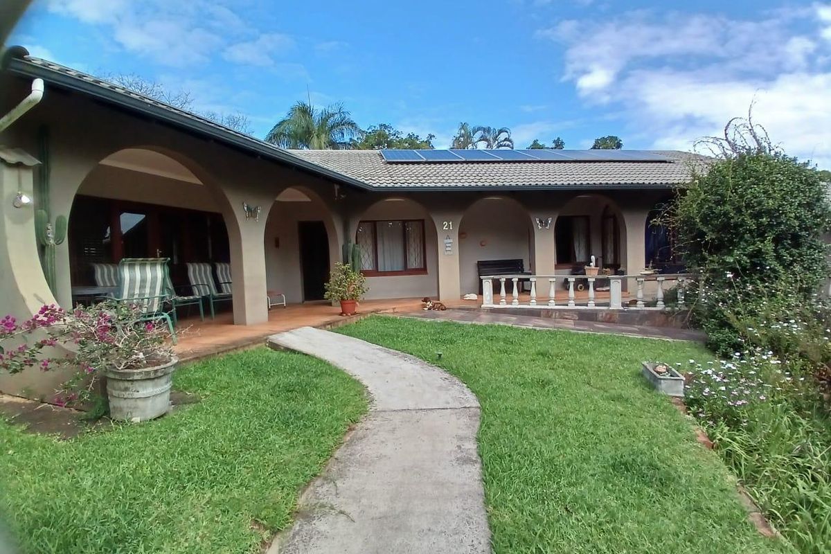 Rear view of the house featuring a covered arched patio, concrete pathway, landscaped garden, and roof-mounted solar panels.