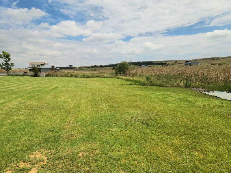 A spacious, well-maintained residential plot featuring expansive green lawn and scenic open landscape views.