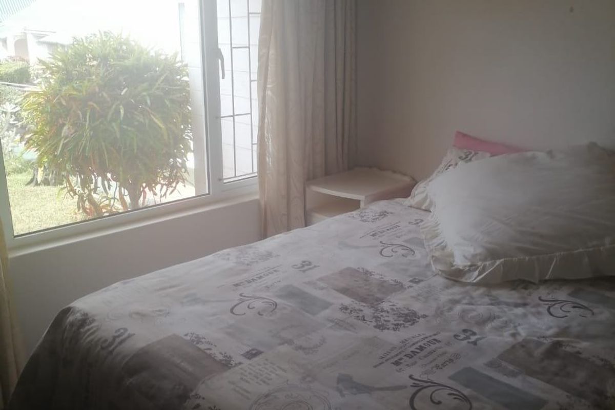 A bedroom featuring a large window with natural light, providing a view of the exterior garden area.