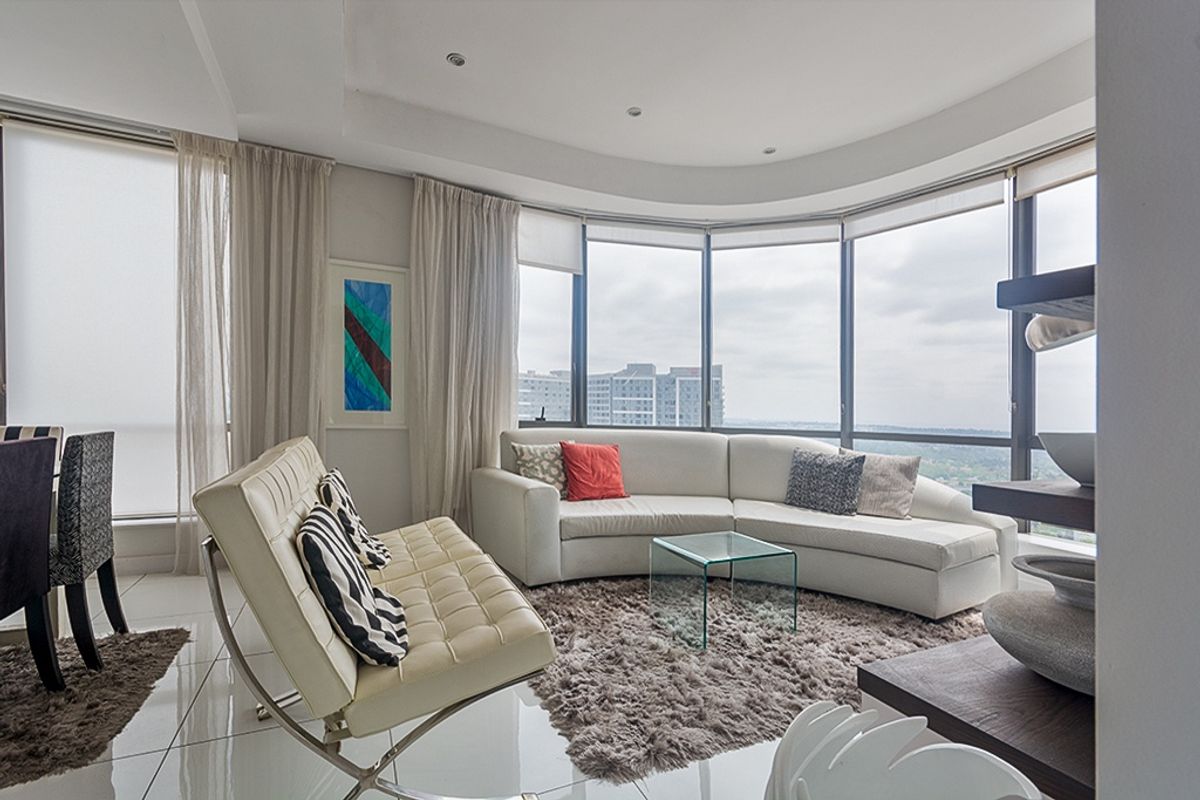 A bright, modern living room featuring expansive floor-to-ceiling curved windows that offer panoramic views and abundant natural light.