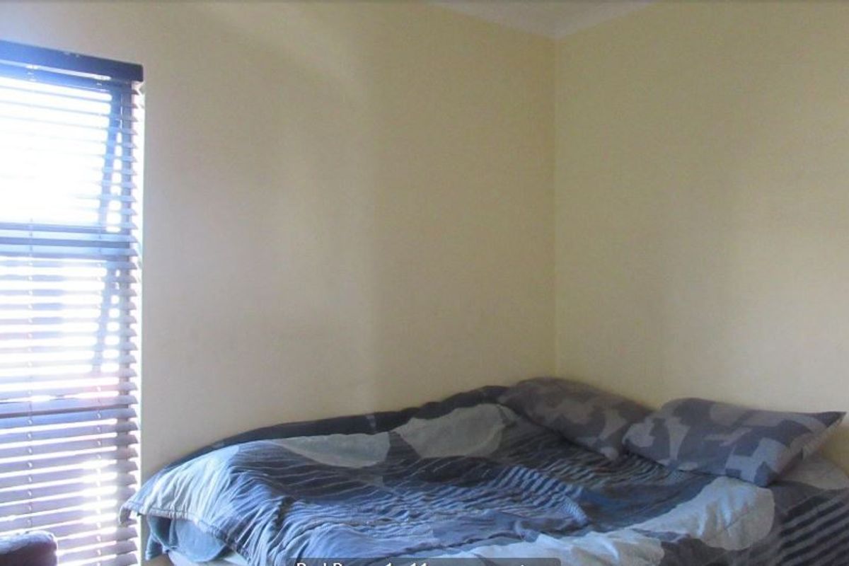 A simple bedroom featuring neutral walls and fitted venetian blinds, providing a functional space with natural light.