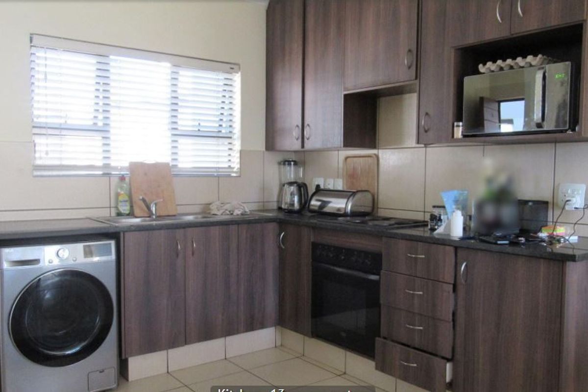 A functional kitchen featuring dark wood-look cabinetry, granite countertops, a tiled backsplash, and integrated appliances including an oven and hob.