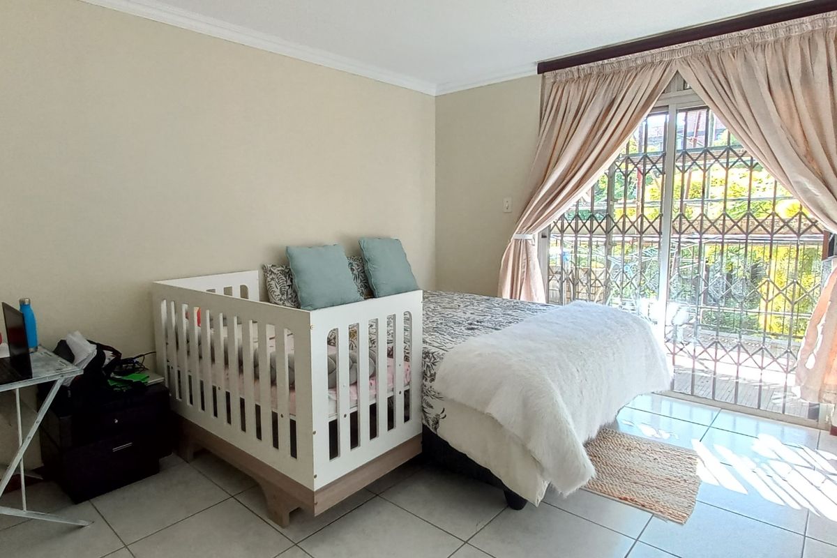 A bedroom featuring tiled flooring and a sliding glass door with security gate, providing access to an outdoor area.