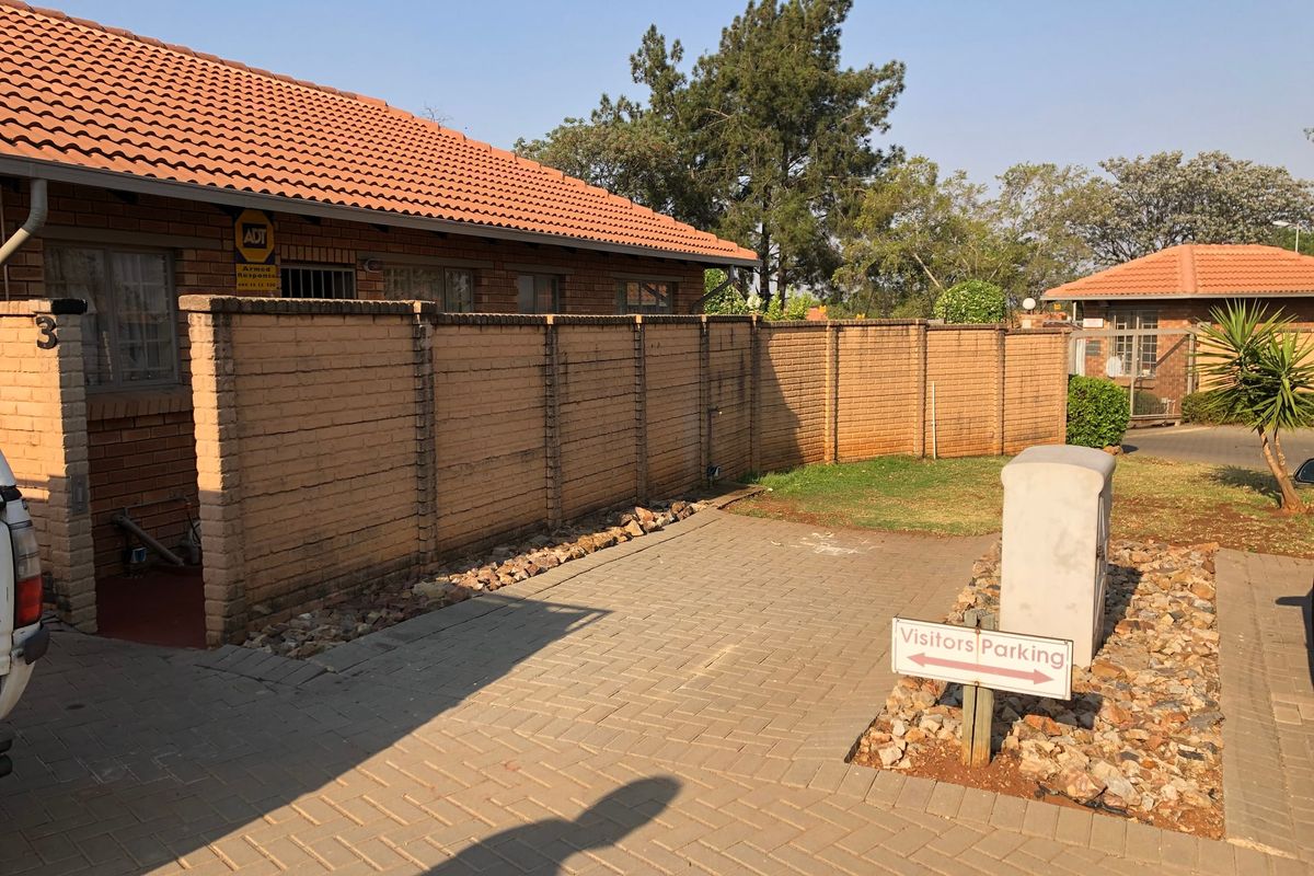 Front exterior view of the property featuring a brick boundary wall, paved driveway, and tiled roof structure.