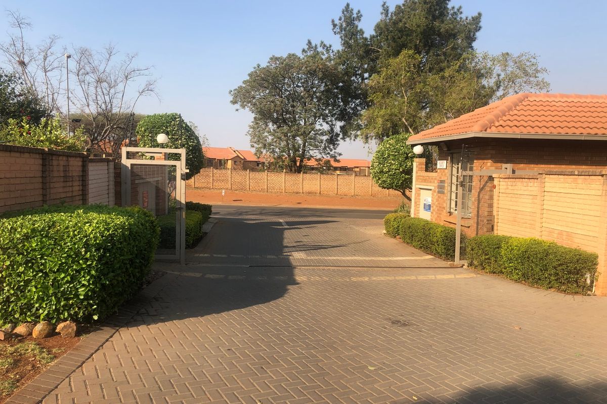 A secure gated entrance to the property featuring a brick guard house, paved driveway, and established perimeter walling.