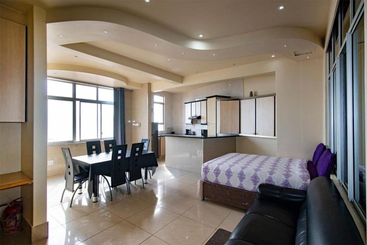 Spacious open-plan living area featuring a modern kitchen with island, tiled floors, and a unique coffered ceiling with recessed lighting.