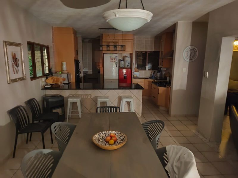 Open-plan kitchen and dining area featuring tiled flooring, granite countertops, and built-in cabinetry, providing a functional space for cooking and casual dining.