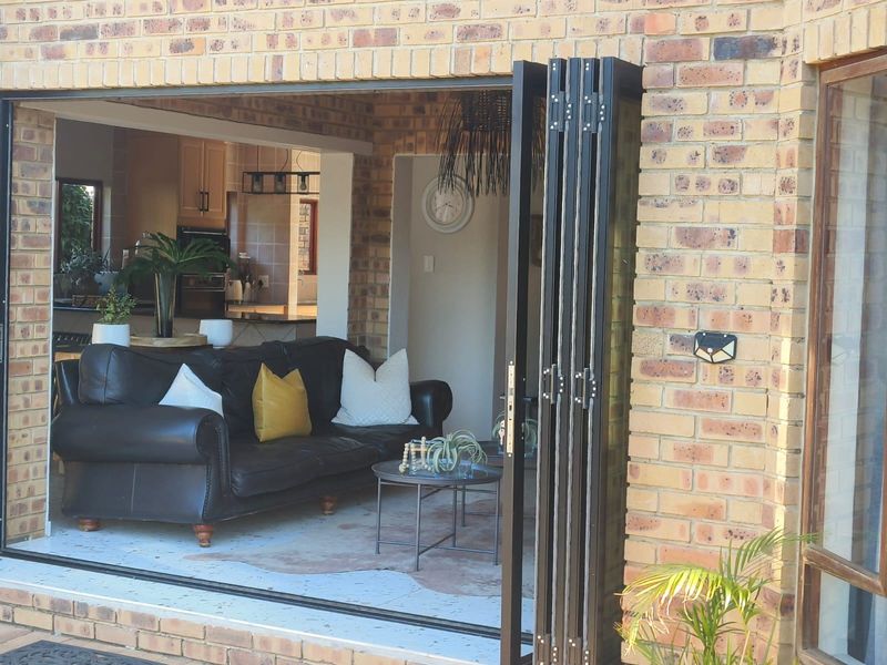 A covered patio area featuring modern black stacking doors that open into the living space, finished with face brick walls and tiled flooring.
