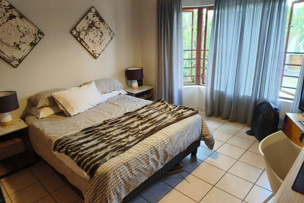 A bedroom featuring tiled flooring and large casement windows that provide natural light and garden views.