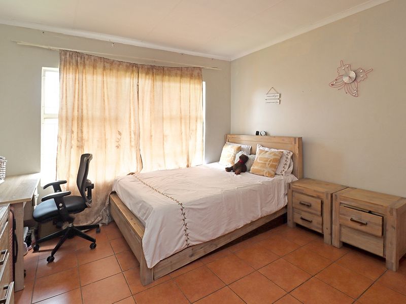 A functional bedroom featuring tiled flooring and natural light from a large window.