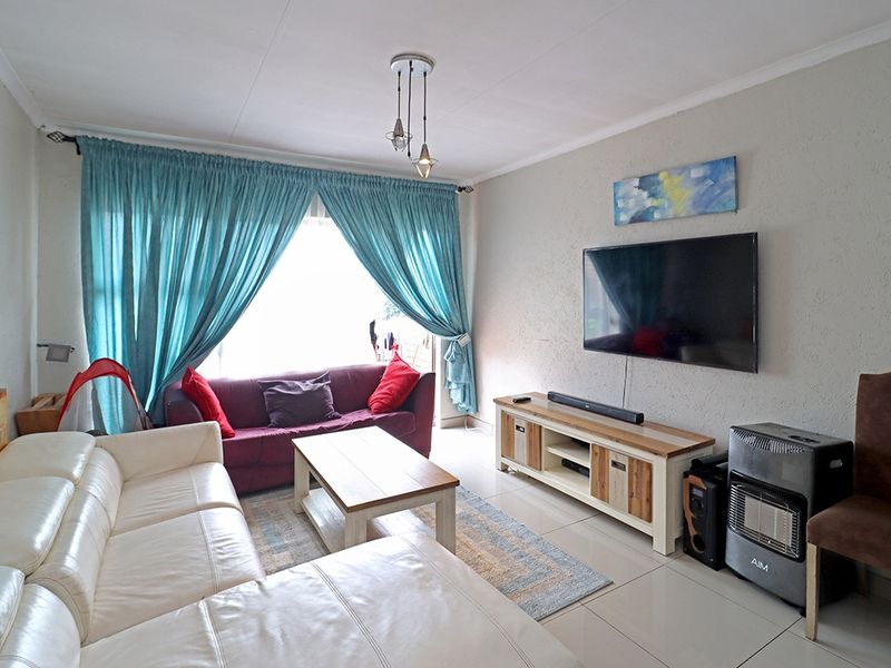 A comfortable living room featuring tiled flooring and neutral wall finishes, providing a functional space for relaxation and entertainment.