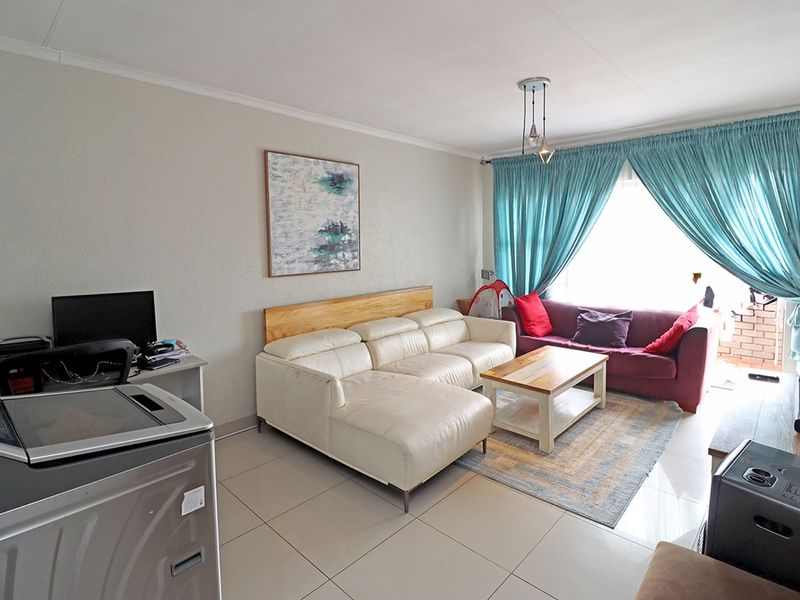 A living room featuring tiled flooring and a sliding glass door providing access to the outdoor area.