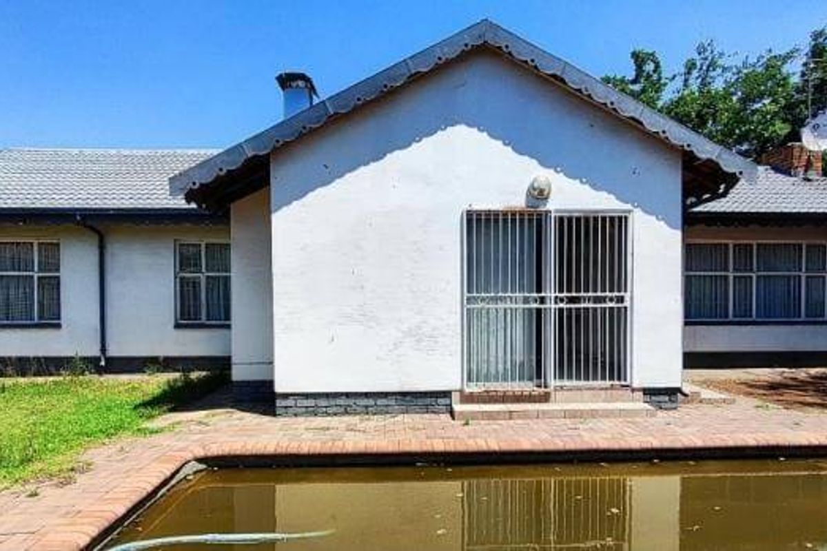 Rear view of the house featuring a swimming pool with paved surround, security gate access, and a tiled roof structure.