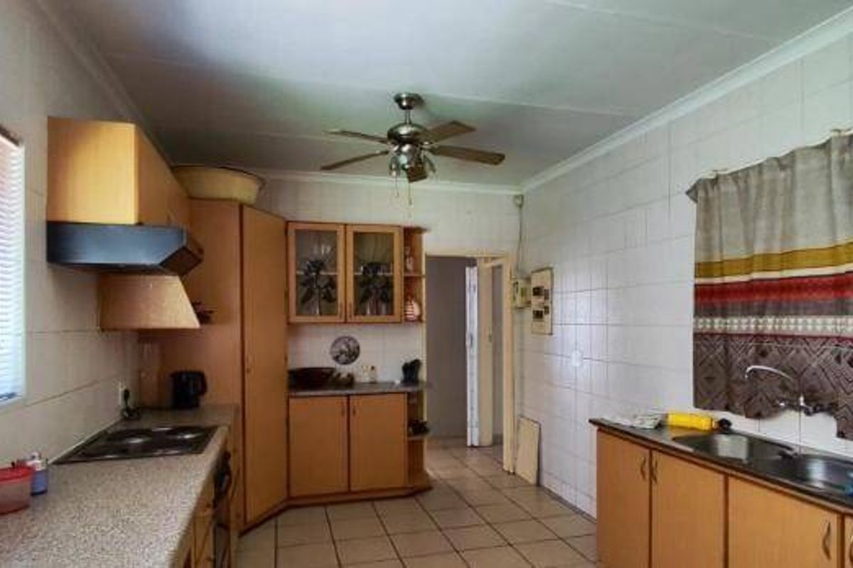 A functional kitchen featuring built-in wooden cabinetry, laminate countertops, a double sink, and an electric hob with an extractor fan.