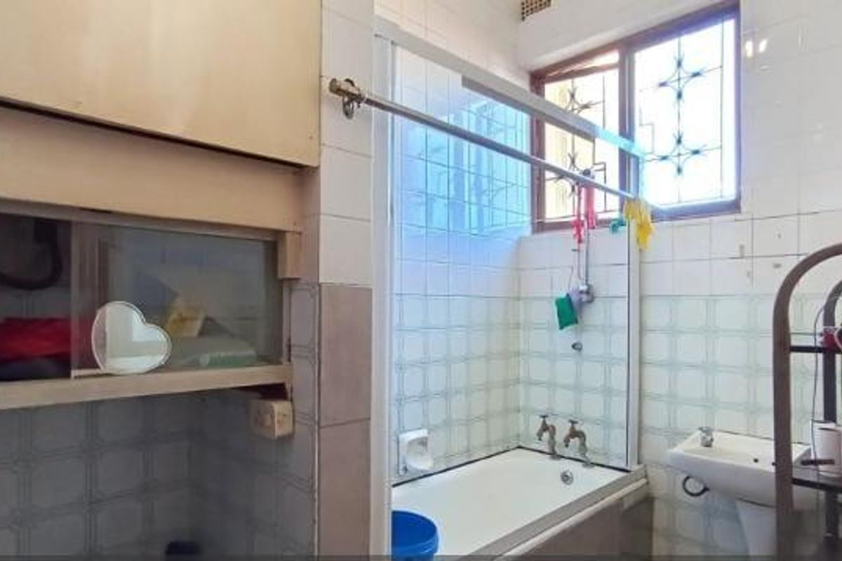 A dated bathroom featuring a bathtub, pedestal basin, and tiled walls, offering potential for a modern renovation to update the space.