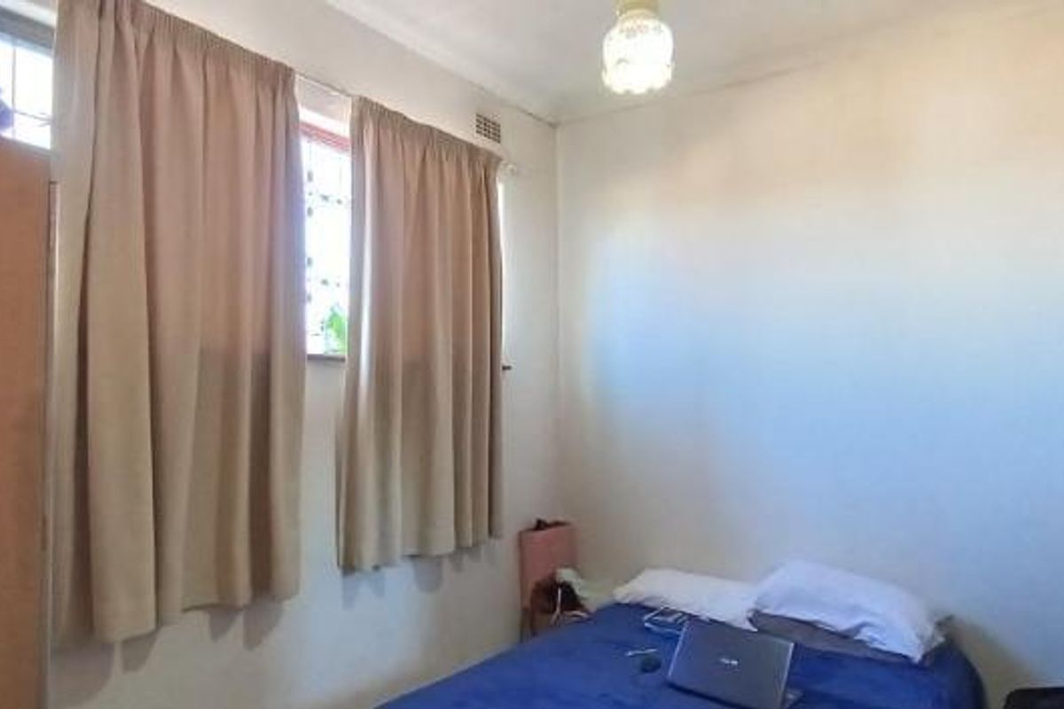 A standard bedroom featuring security bars on the windows and a central ceiling light fixture.