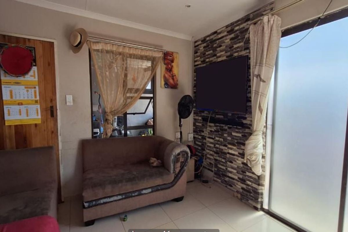 Living room featuring a stone veneer accent wall, tiled flooring, and a sliding glass door providing access to the exterior.