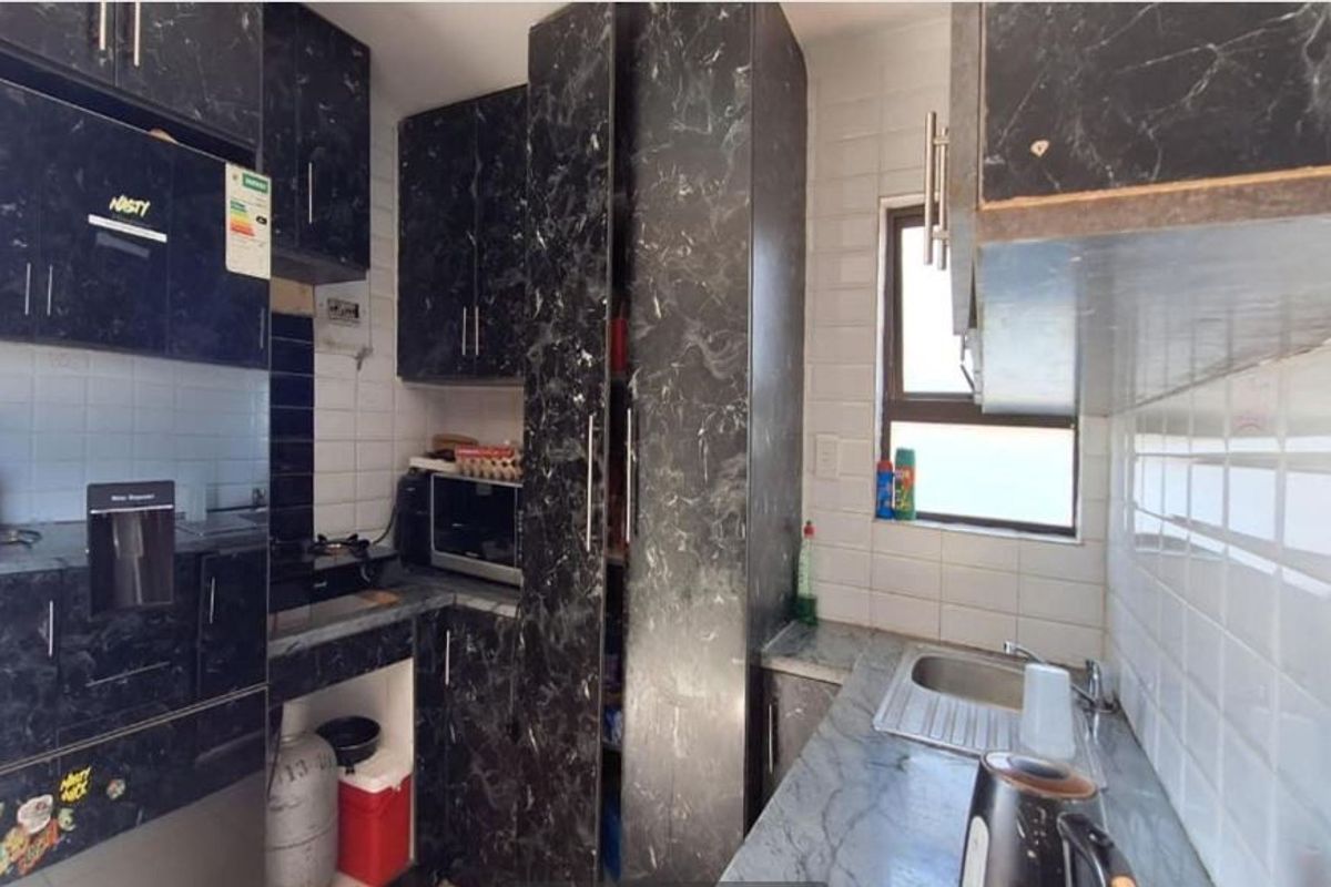 Compact kitchen featuring dark marble-effect cabinetry, tiled backsplash, stainless steel sink, and built-in storage solutions.