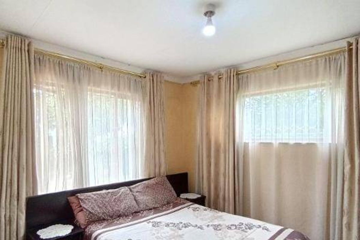 A bedroom featuring neutral wall tones, large windows with installed curtain rods, and decorative coving.