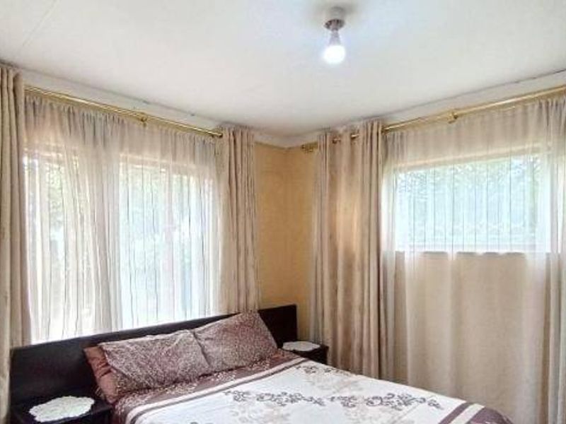 A bedroom featuring neutral wall tones, large windows with installed curtain rods, and decorative coving.