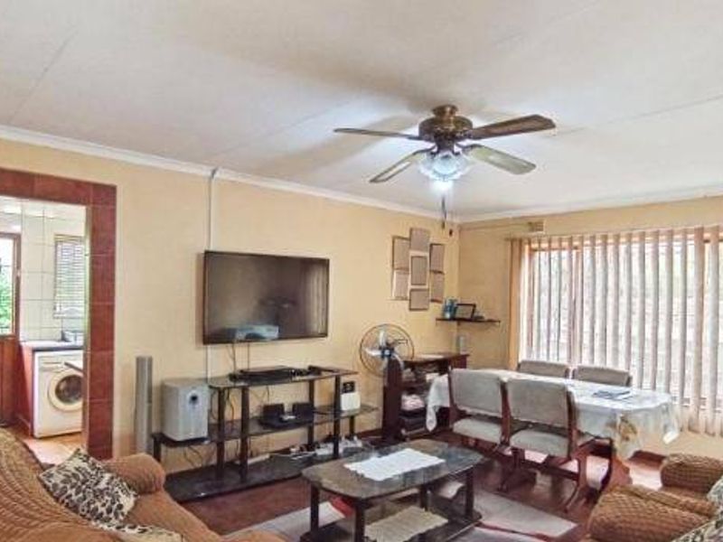 Open plan living and dining area featuring tiled flooring, a ceiling fan, and large windows with vertical blinds, providing a functional and connected living space.